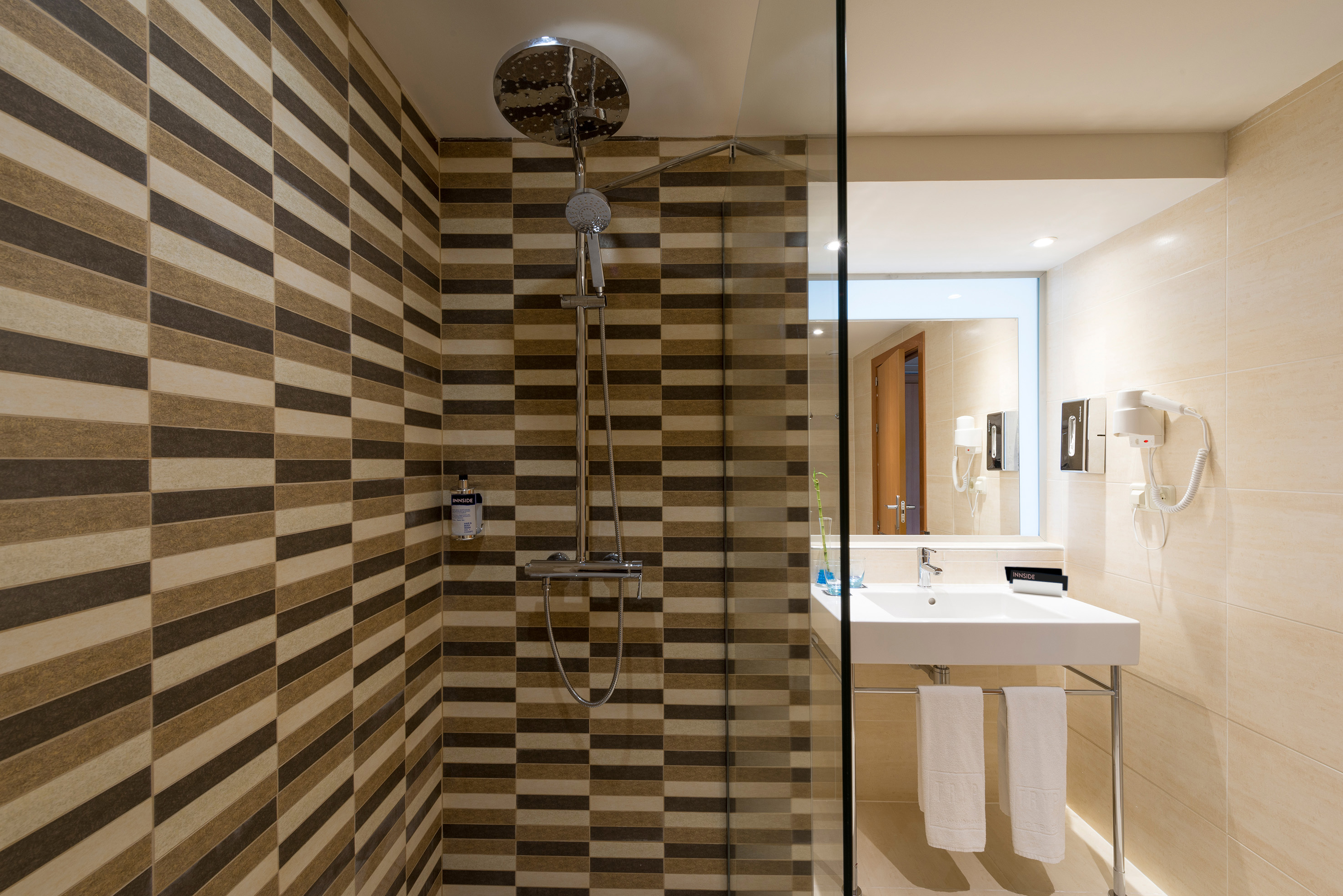 Modern Innside bathroom featuring tiled shower, rain head, and white vanity.