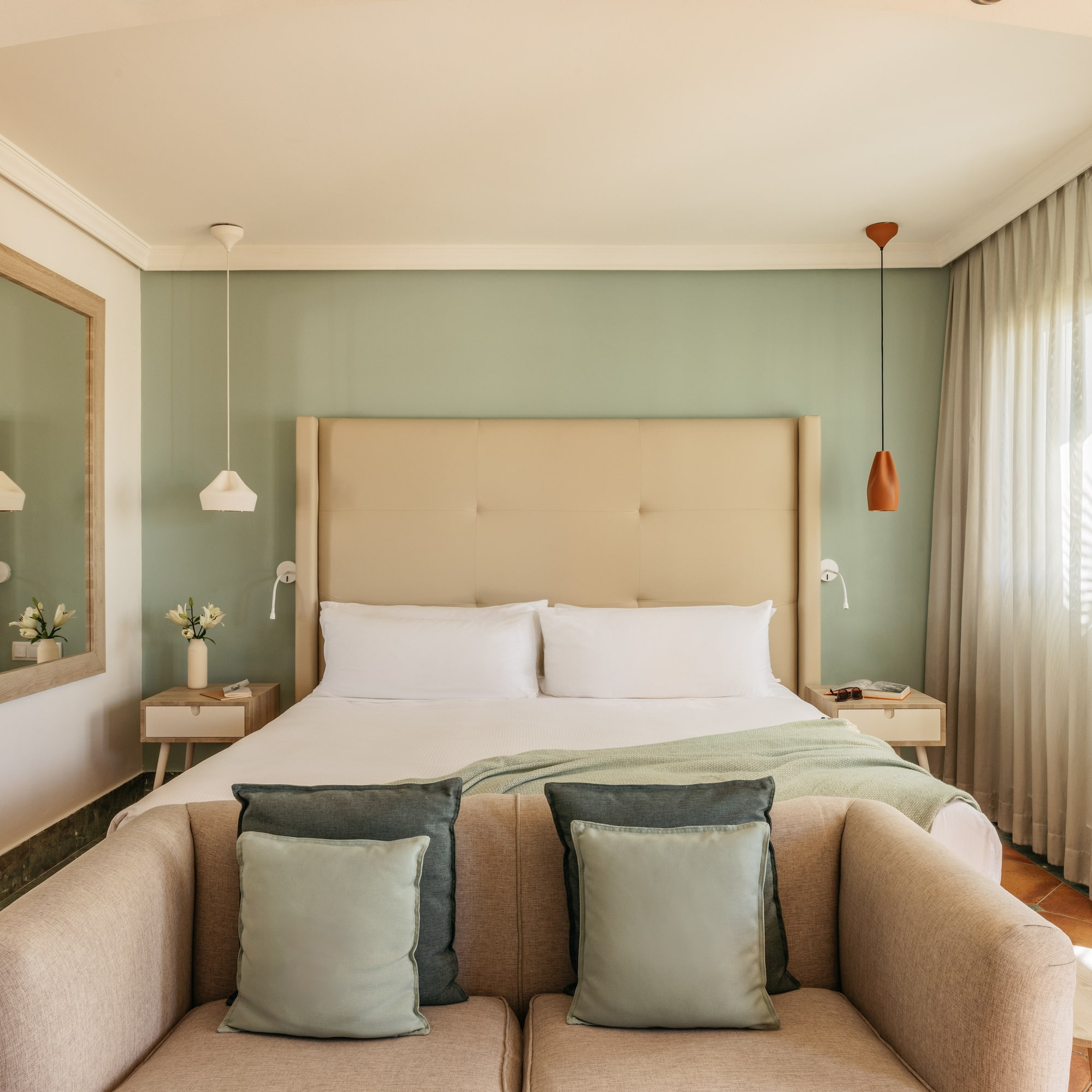 Cozy modern hotel bedroom featuring a green wall, large bed, and comfortable sofa.