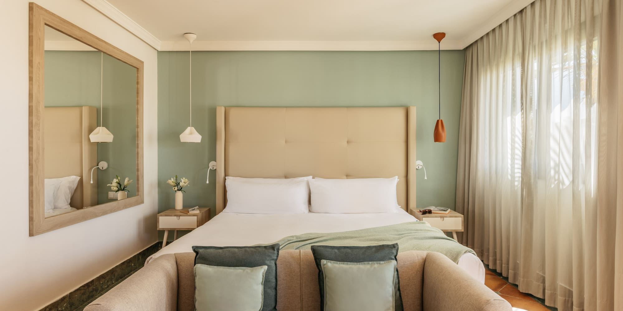 Cozy modern hotel bedroom featuring a green wall, large bed, and comfortable sofa.