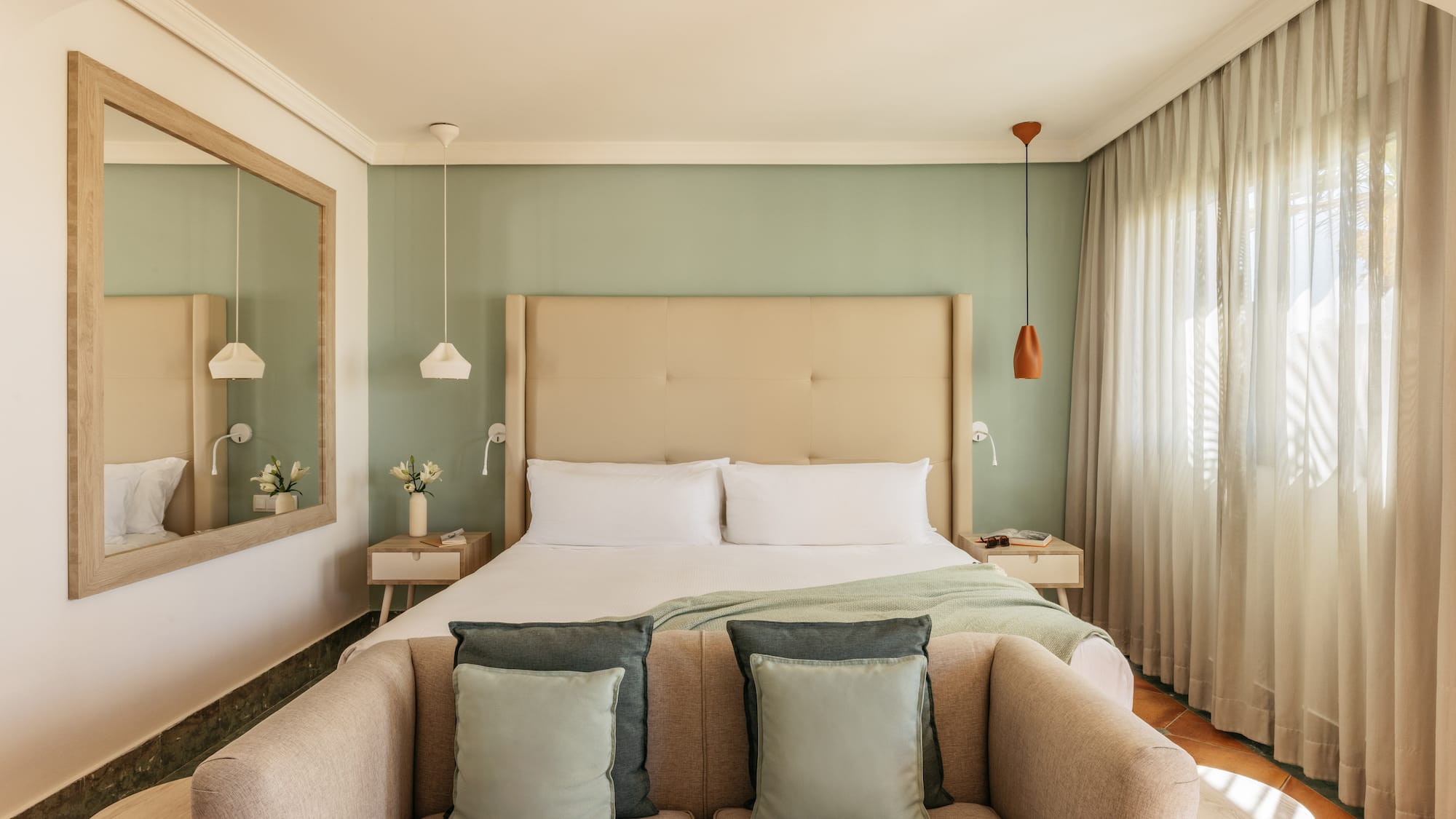 Cozy modern hotel bedroom featuring a green wall, large bed, and comfortable sofa.