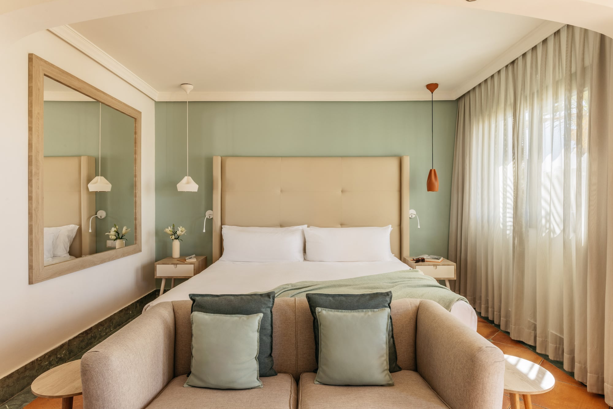 Cozy modern hotel bedroom featuring a green wall, large bed, and comfortable sofa.