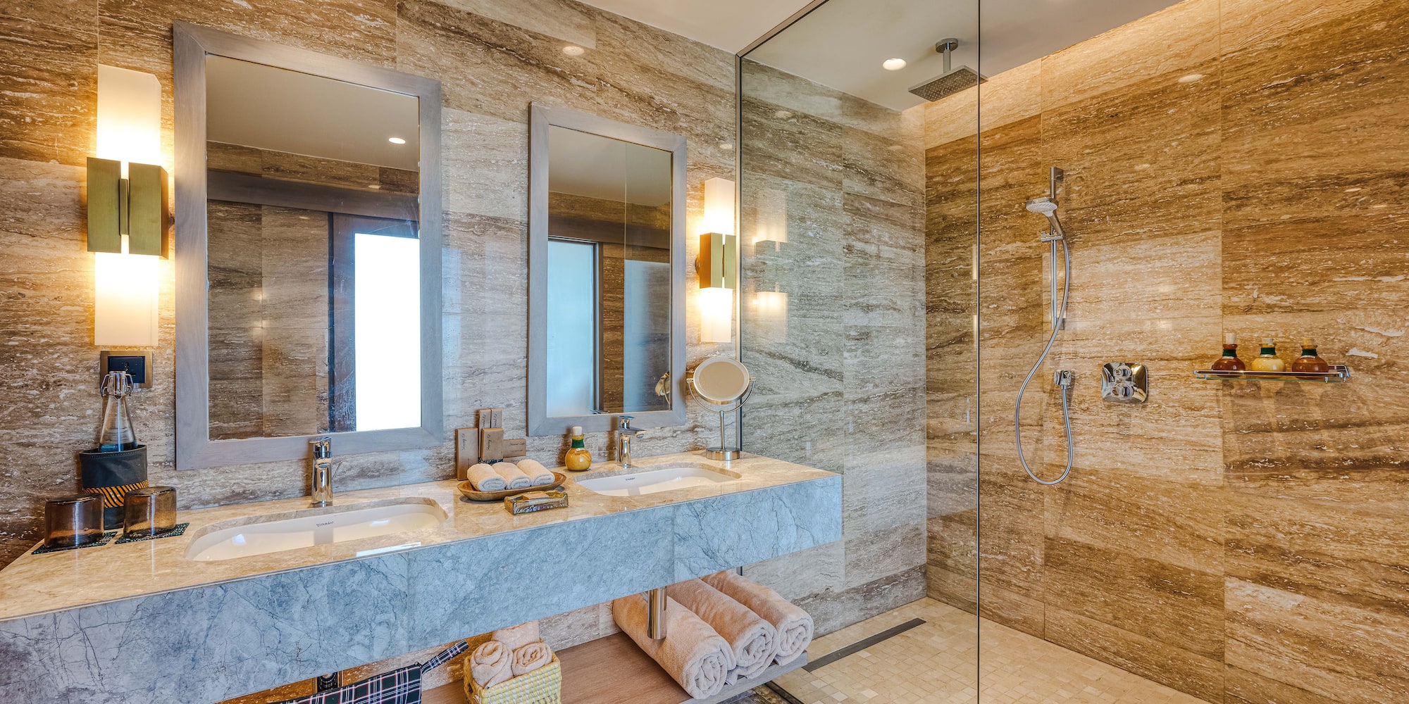 a bathroom with marble countertop sinks and glass shower