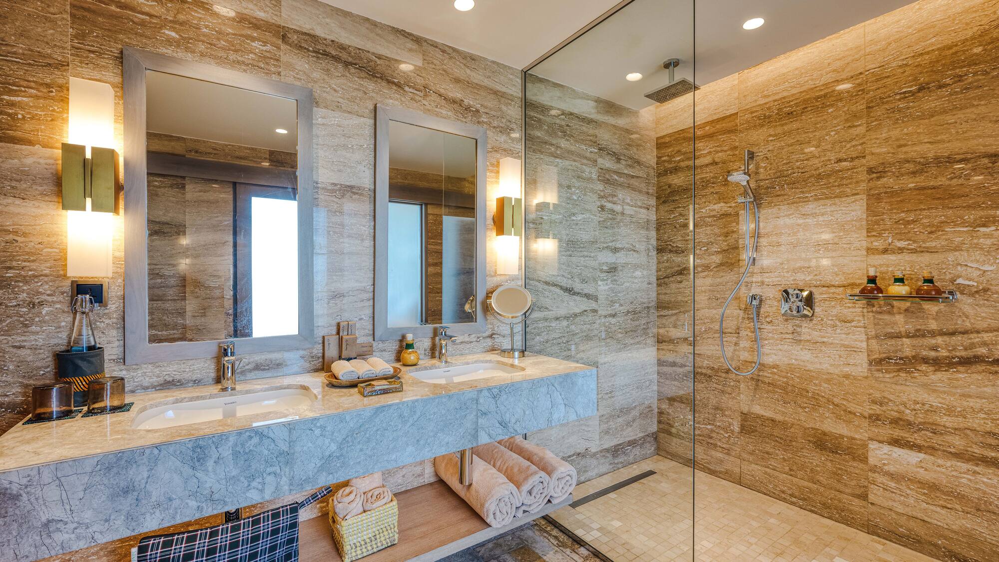 a bathroom with marble countertop sinks and glass shower