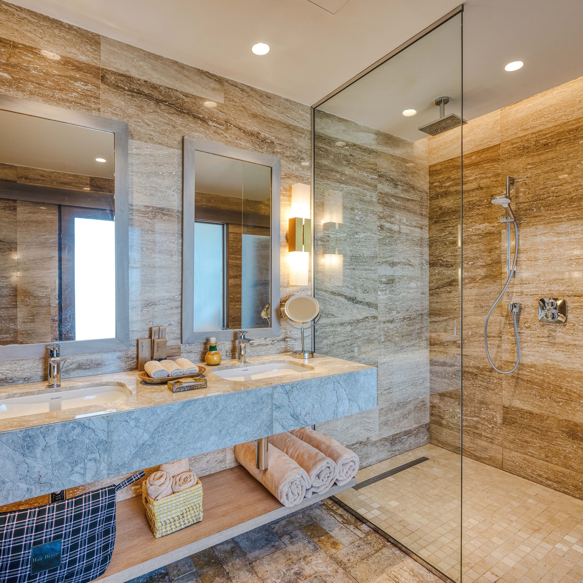 a bathroom with marble countertop sinks and glass shower