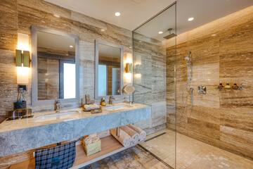 a bathroom with marble countertop sinks and glass shower