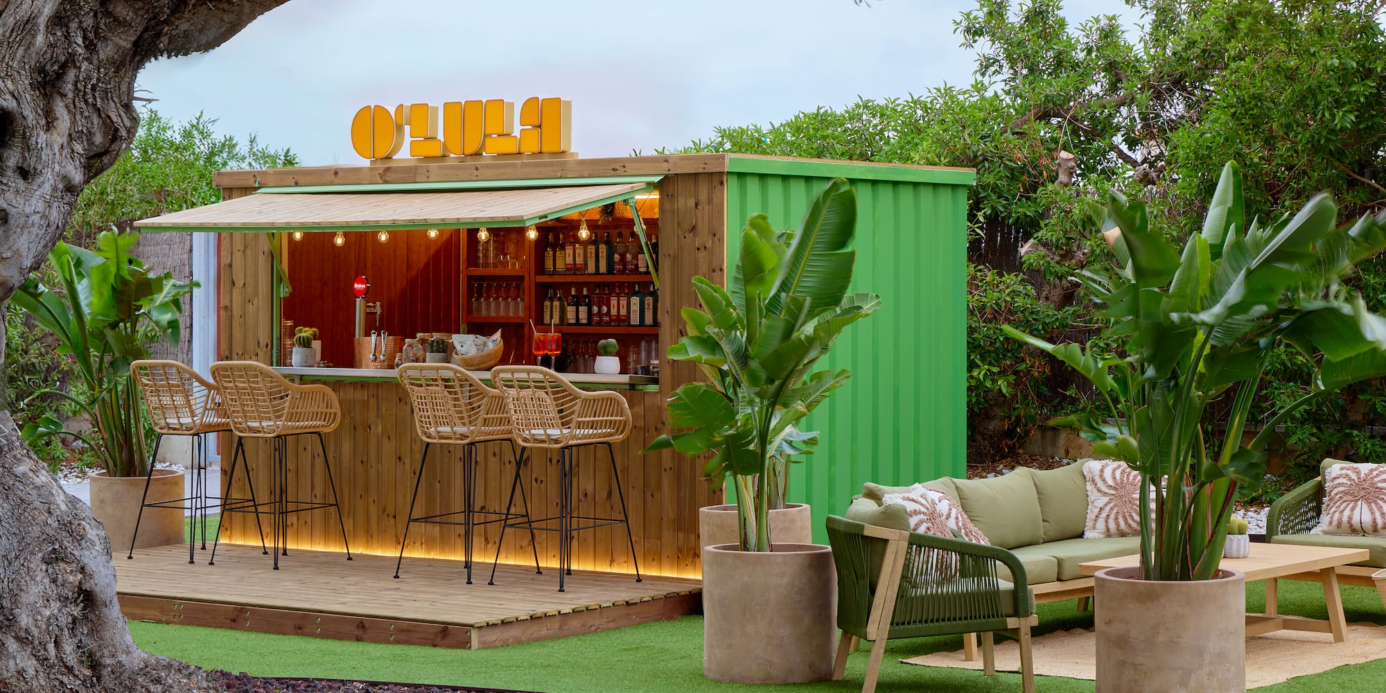 OLULA garden bar, green container design, rattan stools, modern lounge area.