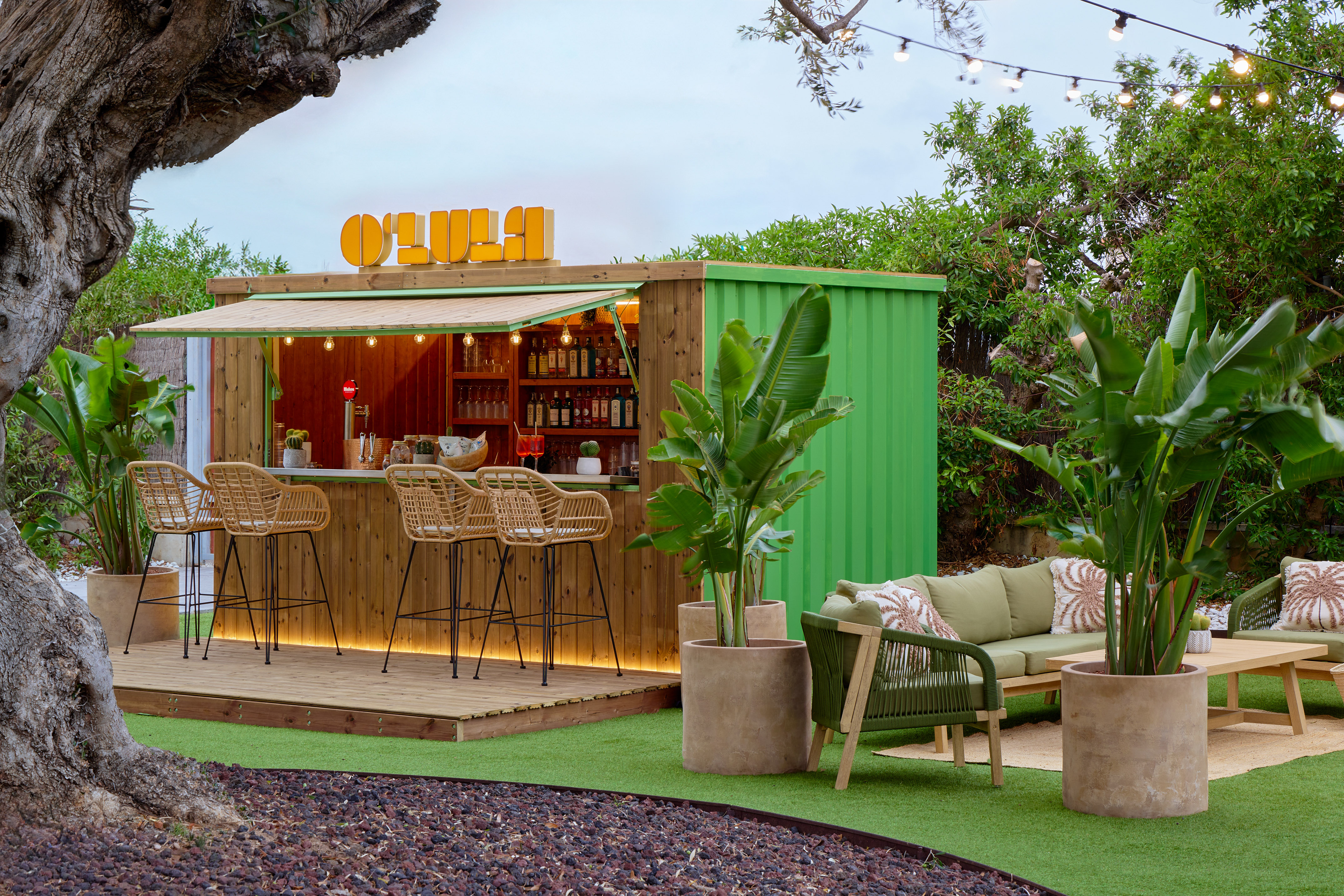 OLULA garden bar, green container design, rattan stools, modern lounge area.