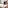 Luxury hotel bedroom with wood paneling, floral wall art, and separate lounge.