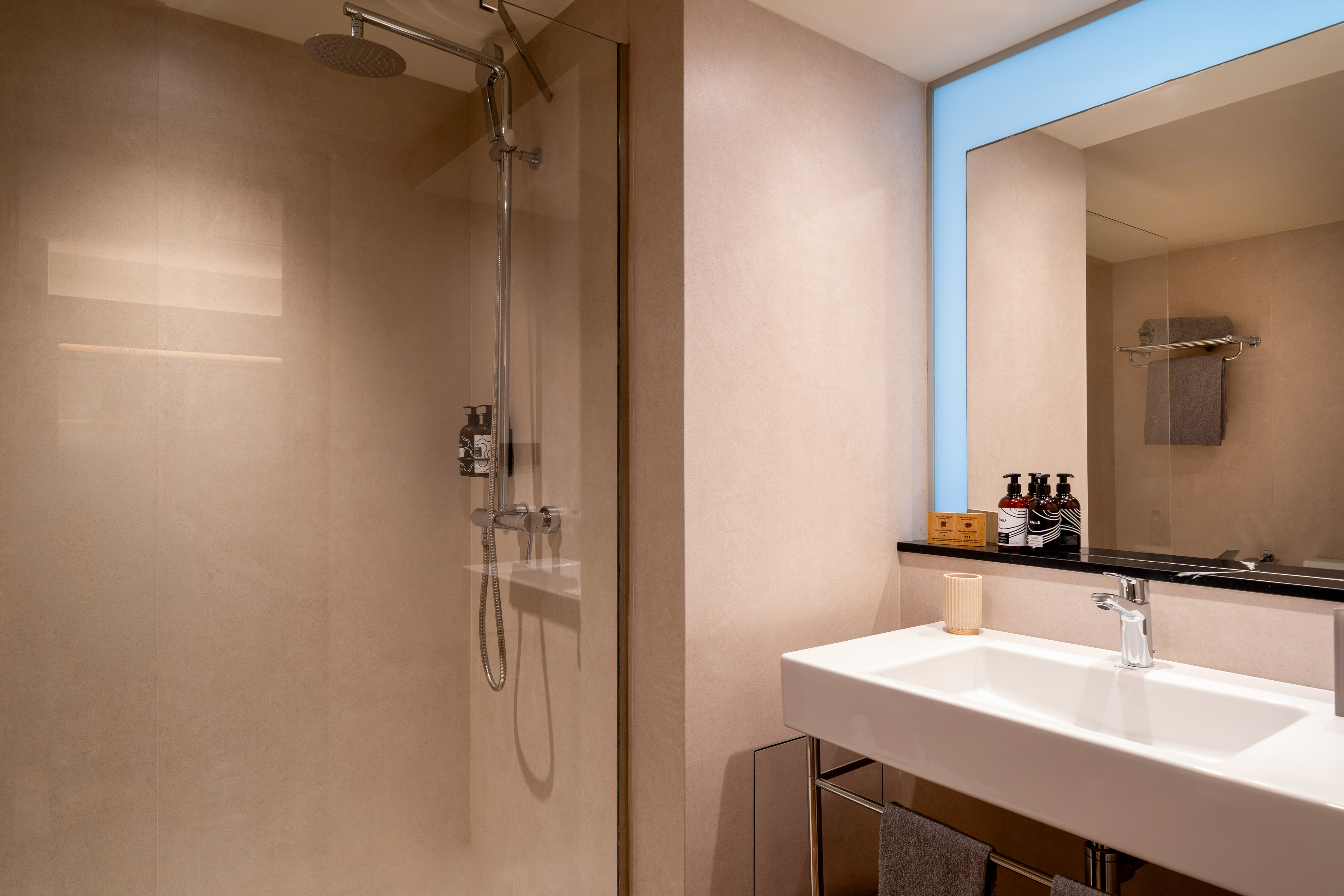 Modern bathroom with beige tiled shower and white sink vanity.