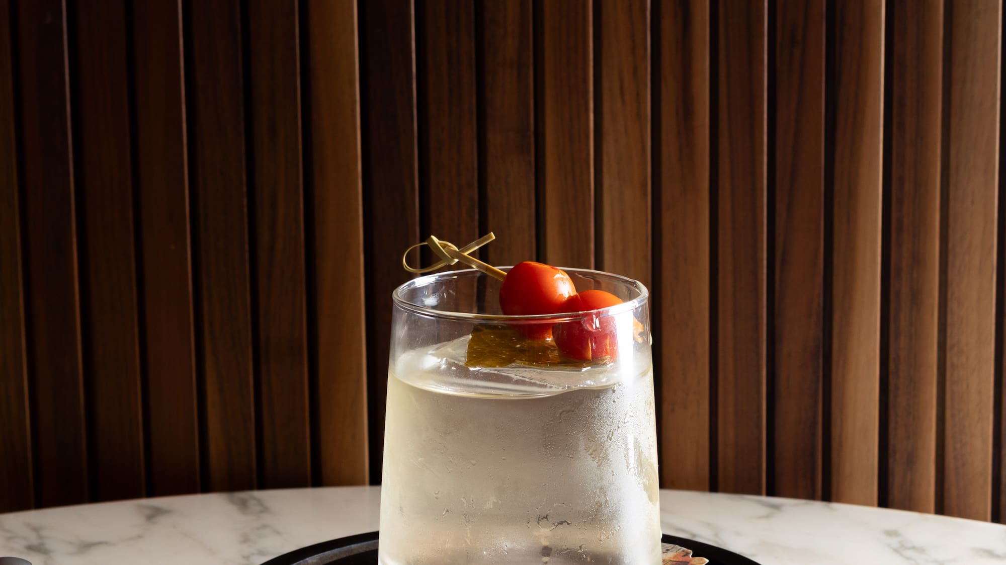 a glass of liquid with cherry tomatoes on top of it