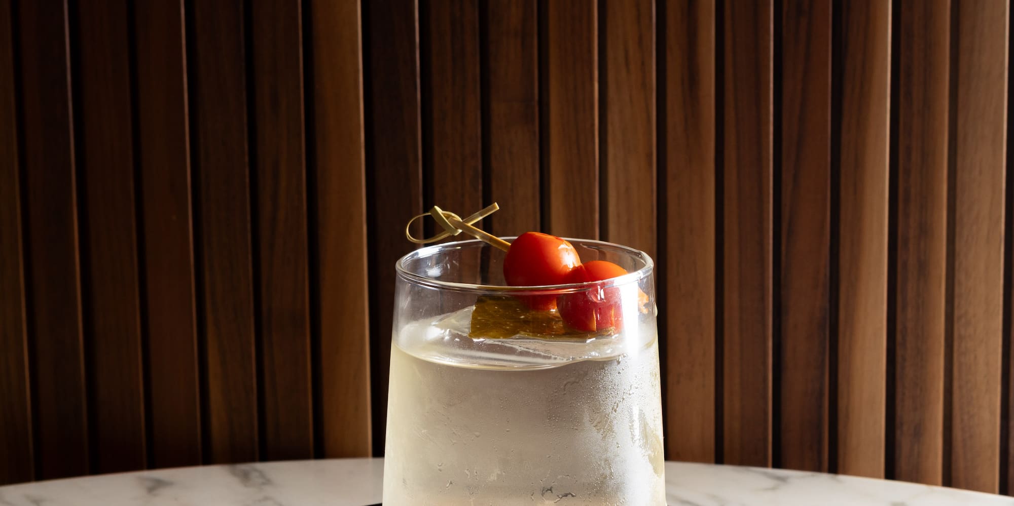 a glass of liquid with cherry tomatoes on top of it