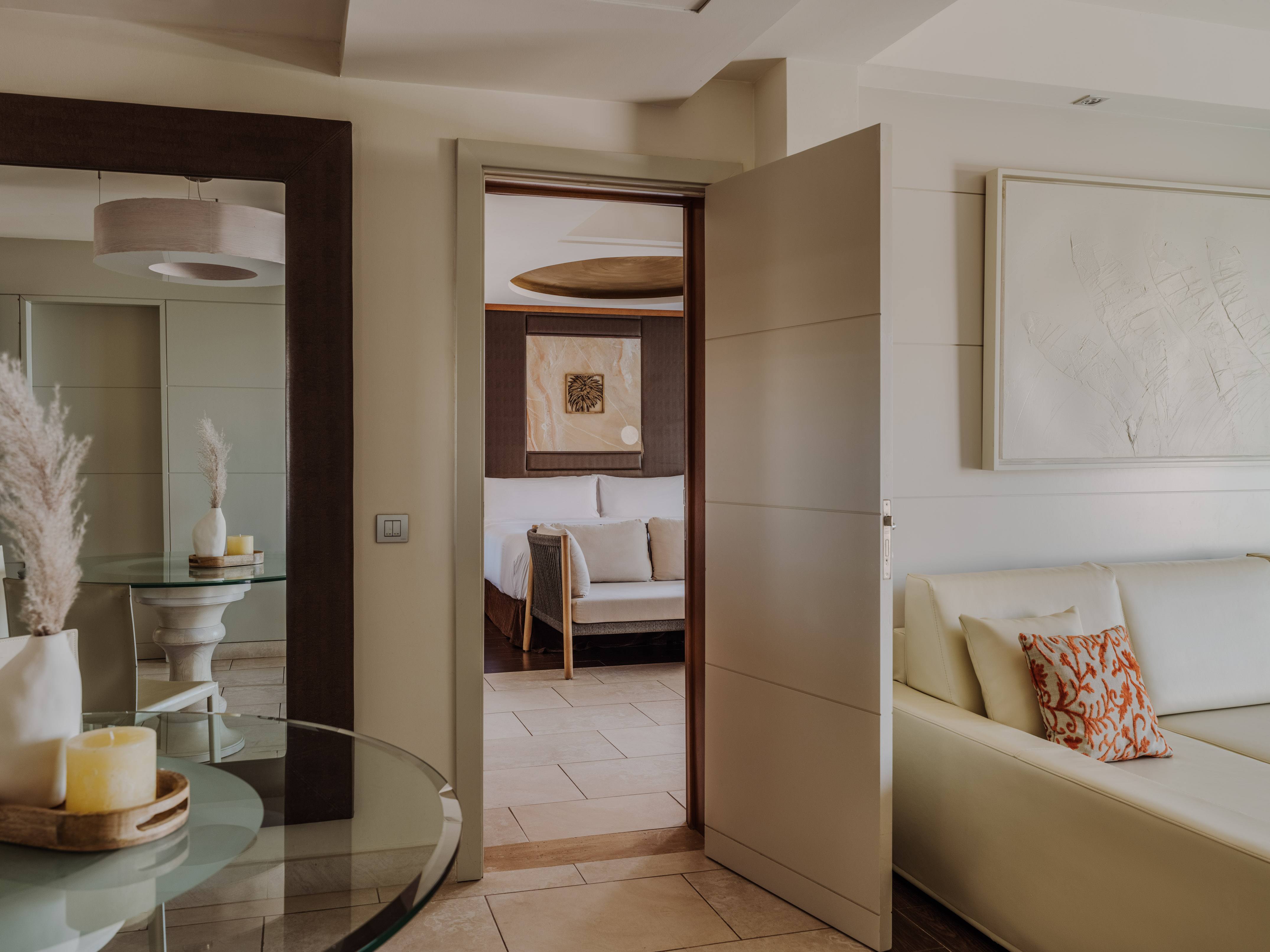 Modern hotel suite with open door connecting living room to bedroom.