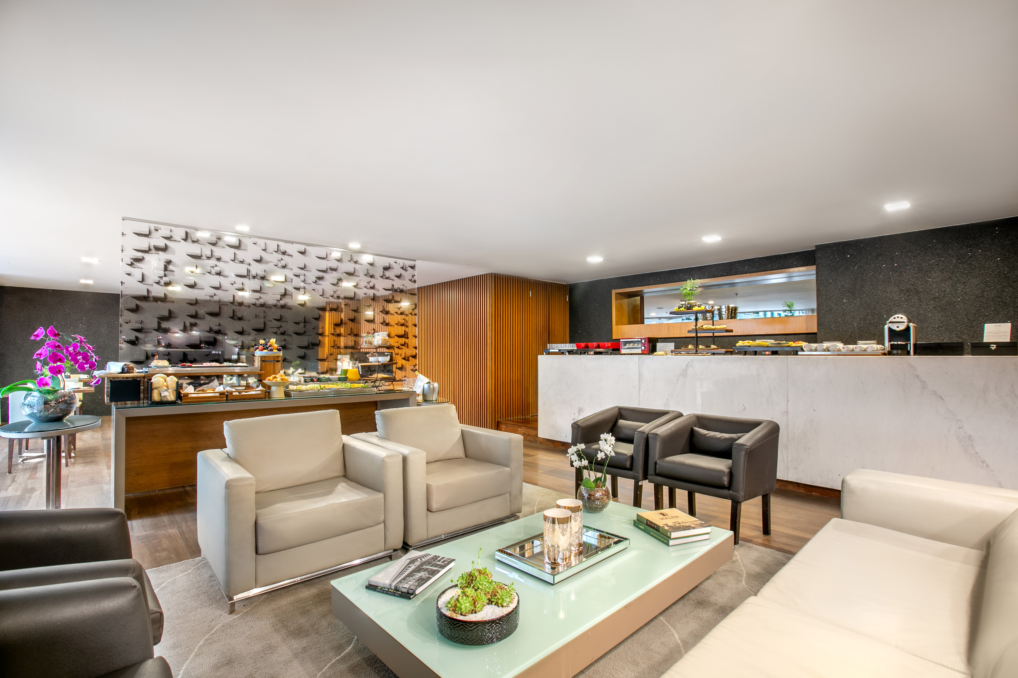 Hotel lounge with modern seating, breakfast buffet, and coffee station.