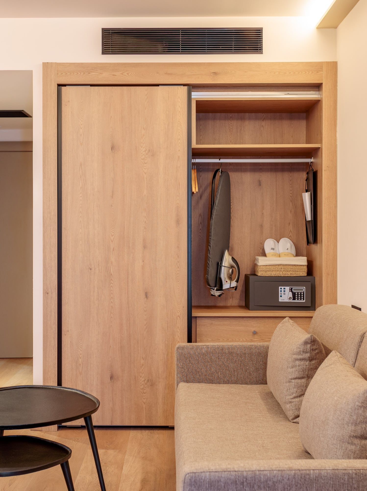 Moderna habitación de hotel con sofá, armario de madera y caja fuerte.