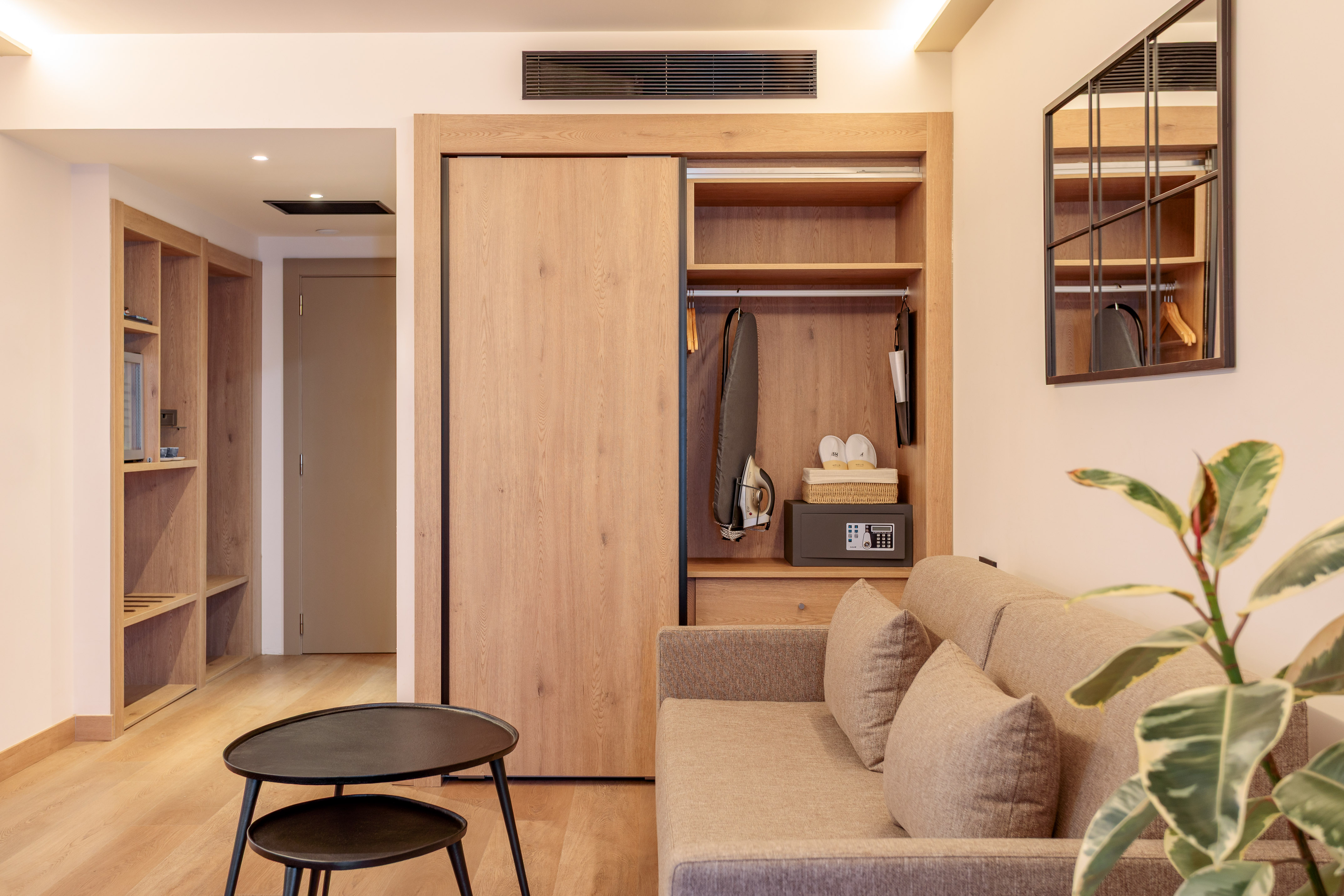 Moderna habitación de hotel con sofá, armario de madera y caja fuerte.