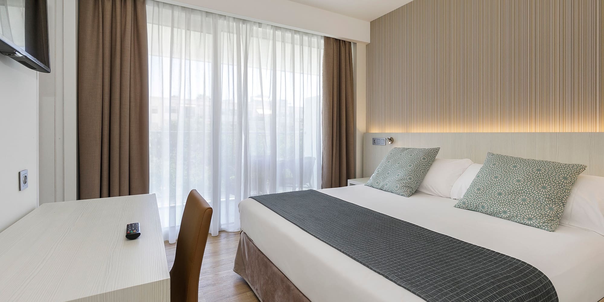a bed with a desk and chair in a hotel room