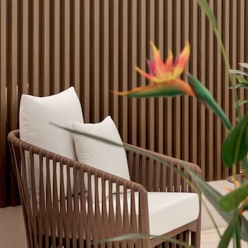 a chair with a white pillow and a flower in front of a wood wall