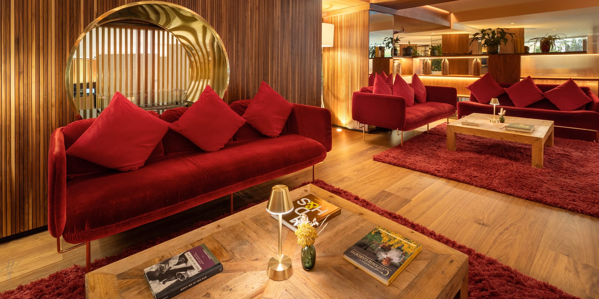 Modern hotel lobby with red velvet sofas, wood accents, and ambient lighting.