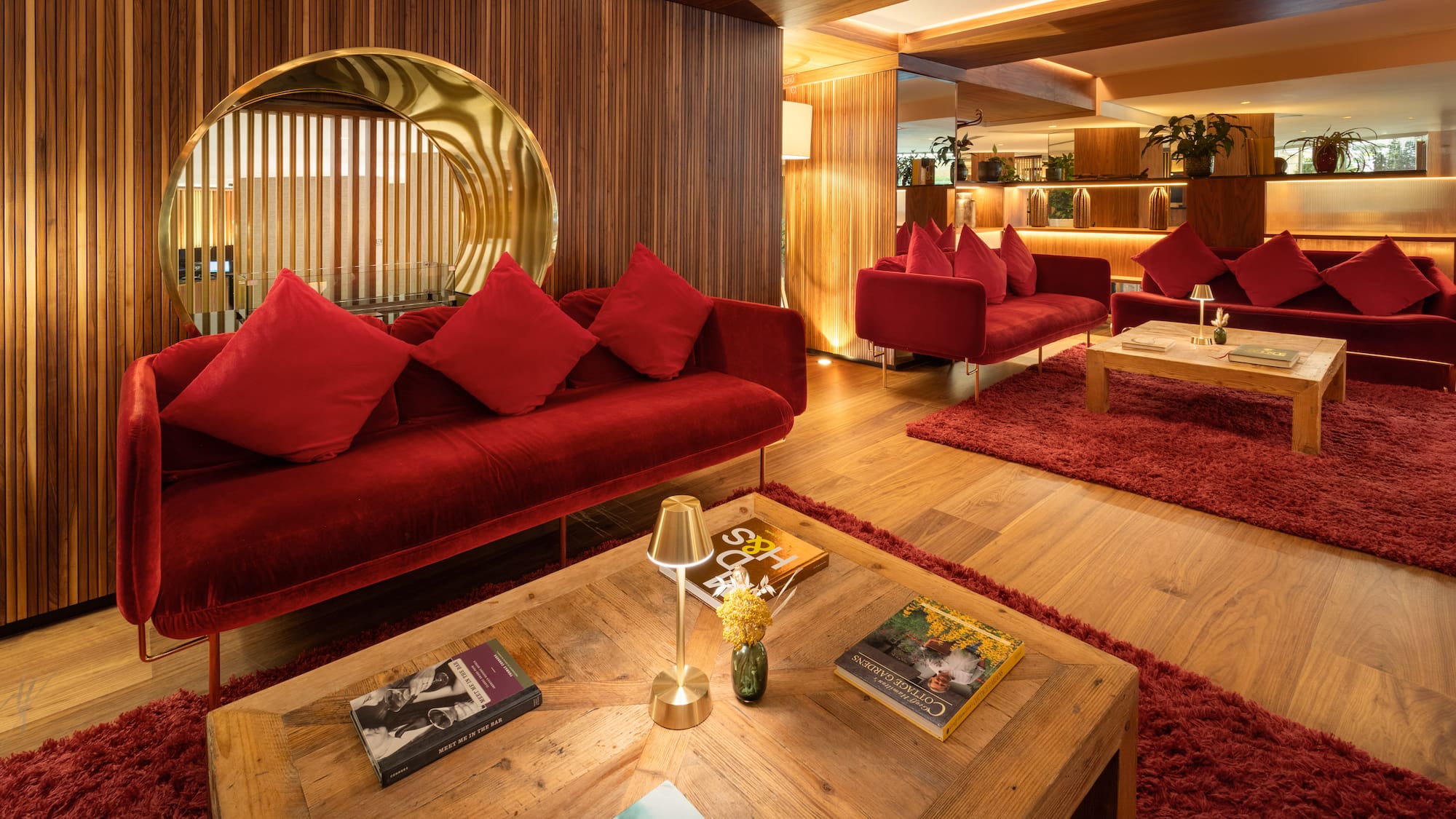 Modern hotel lobby with red velvet sofas, wood accents, and ambient lighting.