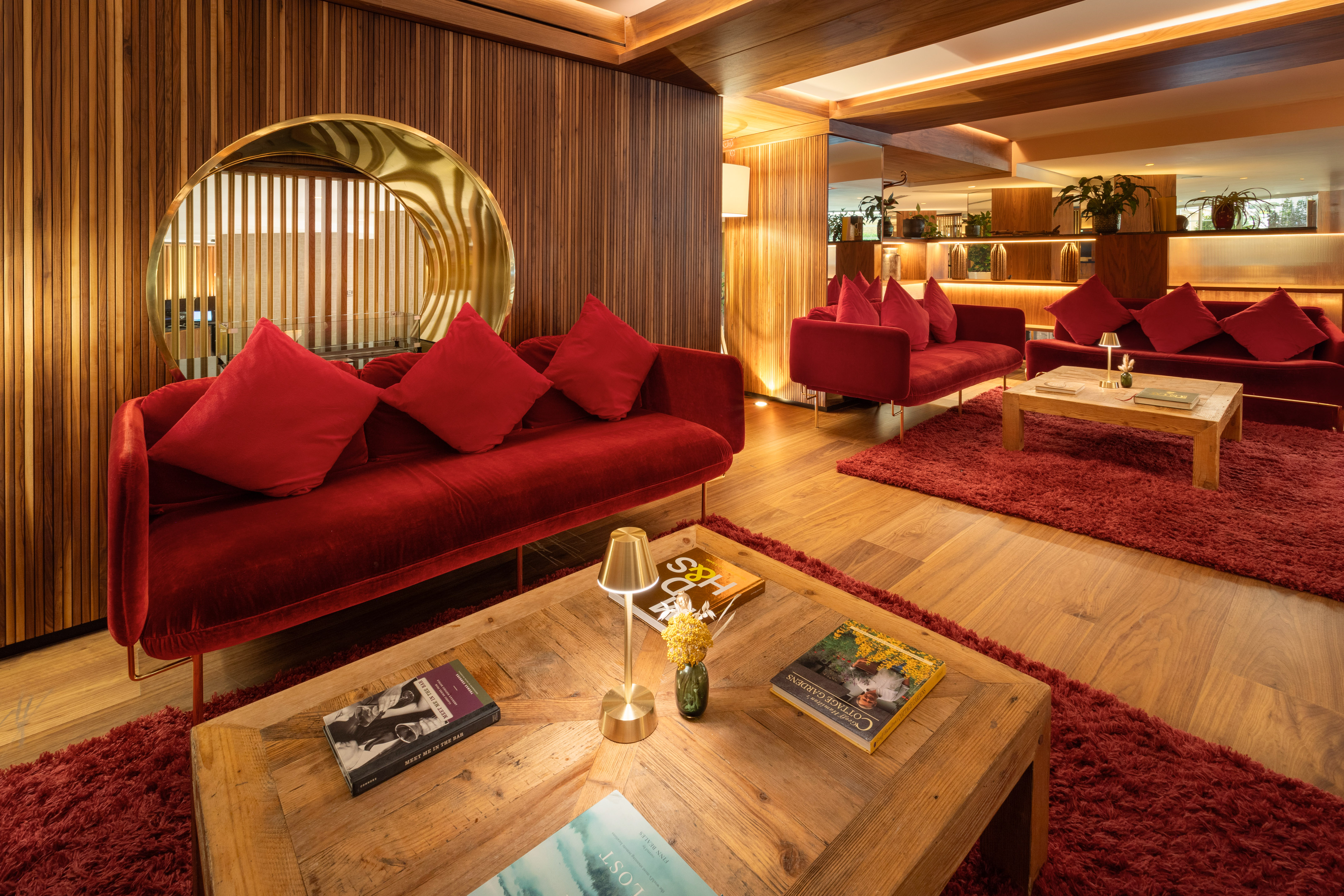 Modern hotel lobby with red velvet sofas, wood accents, and ambient lighting.