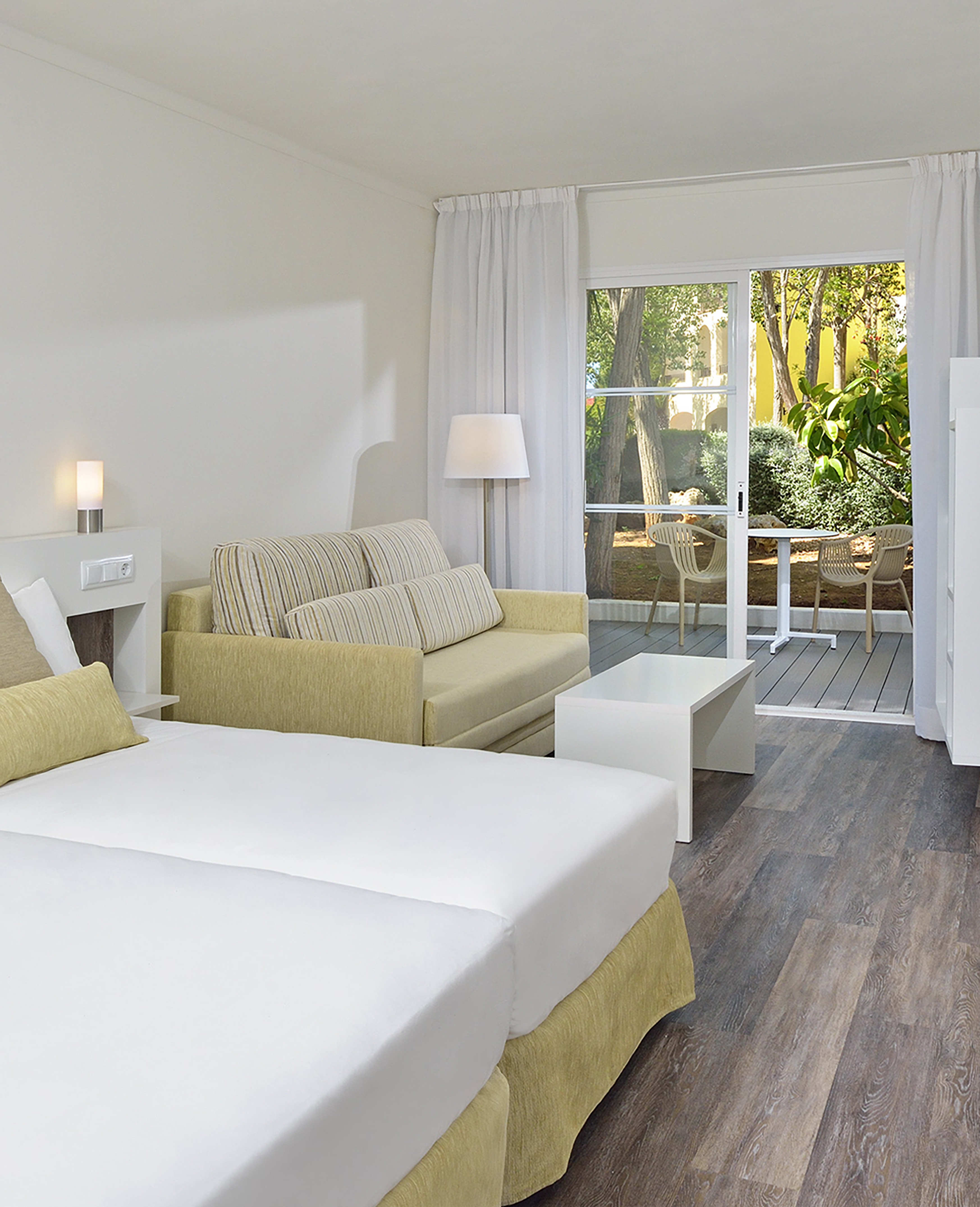 Hotel studio apartment with bed, sofa, and outdoor garden patio.