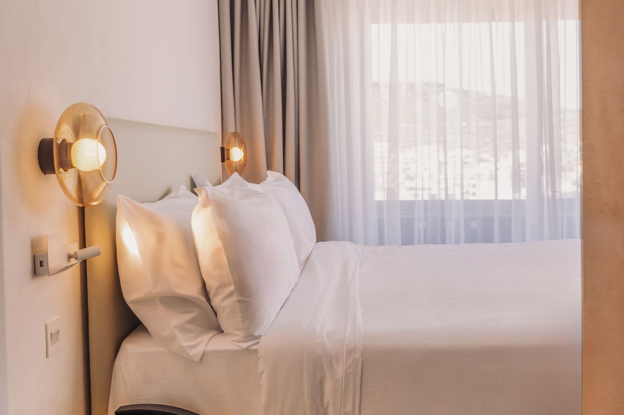 a bed with white sheets and a yellow end table