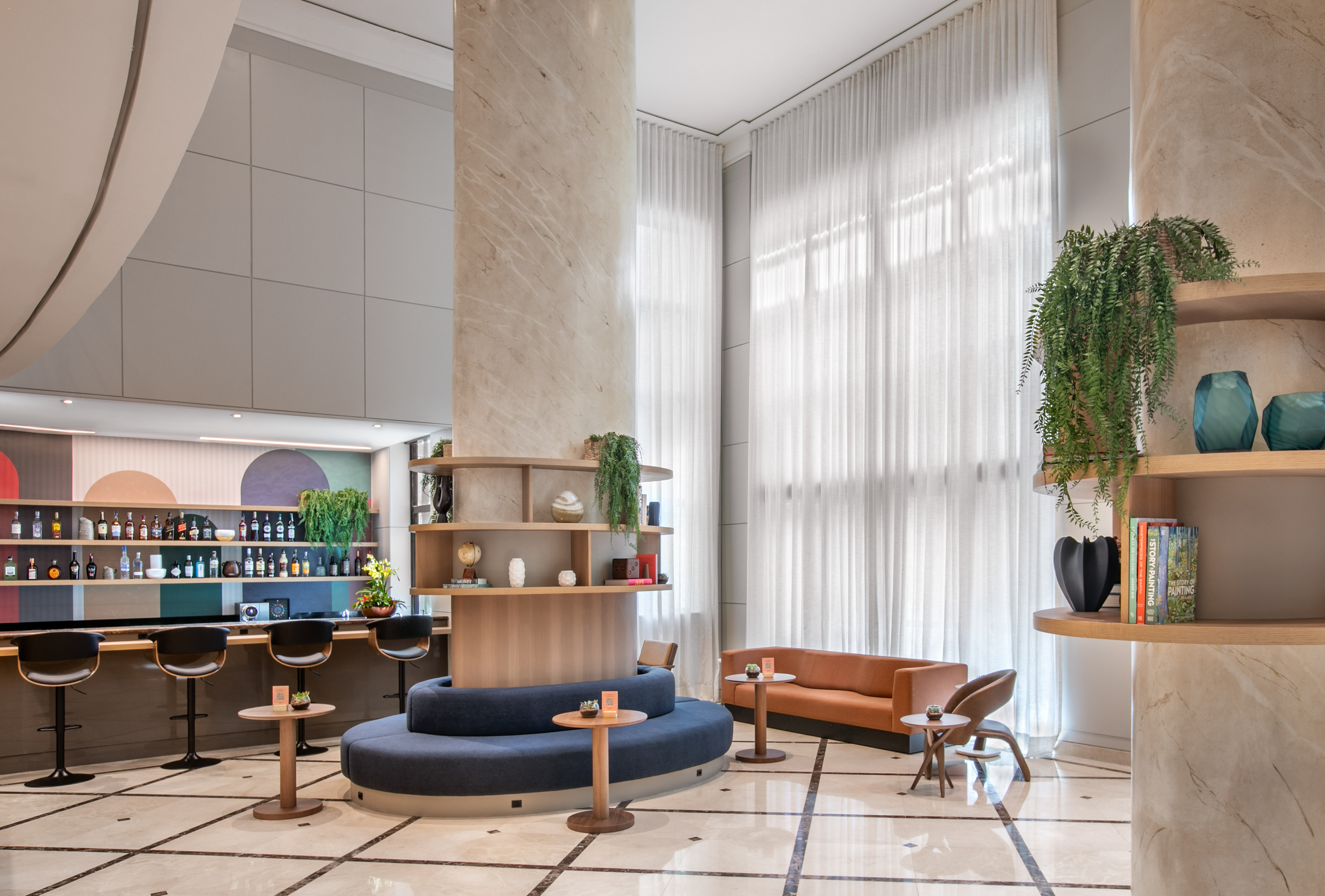 Modern hotel lobby lounge with bar, stylish seating, and decorative plants.