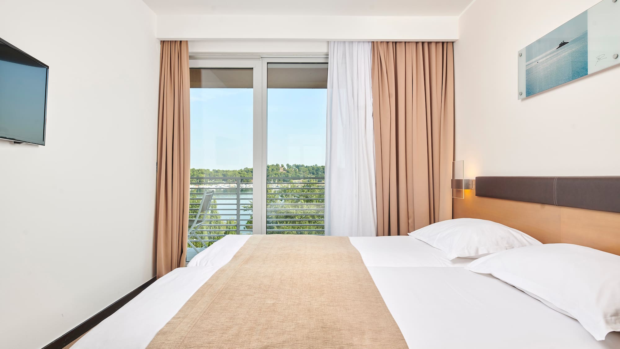 a bed with white sheets and brown blanket in a room with a window