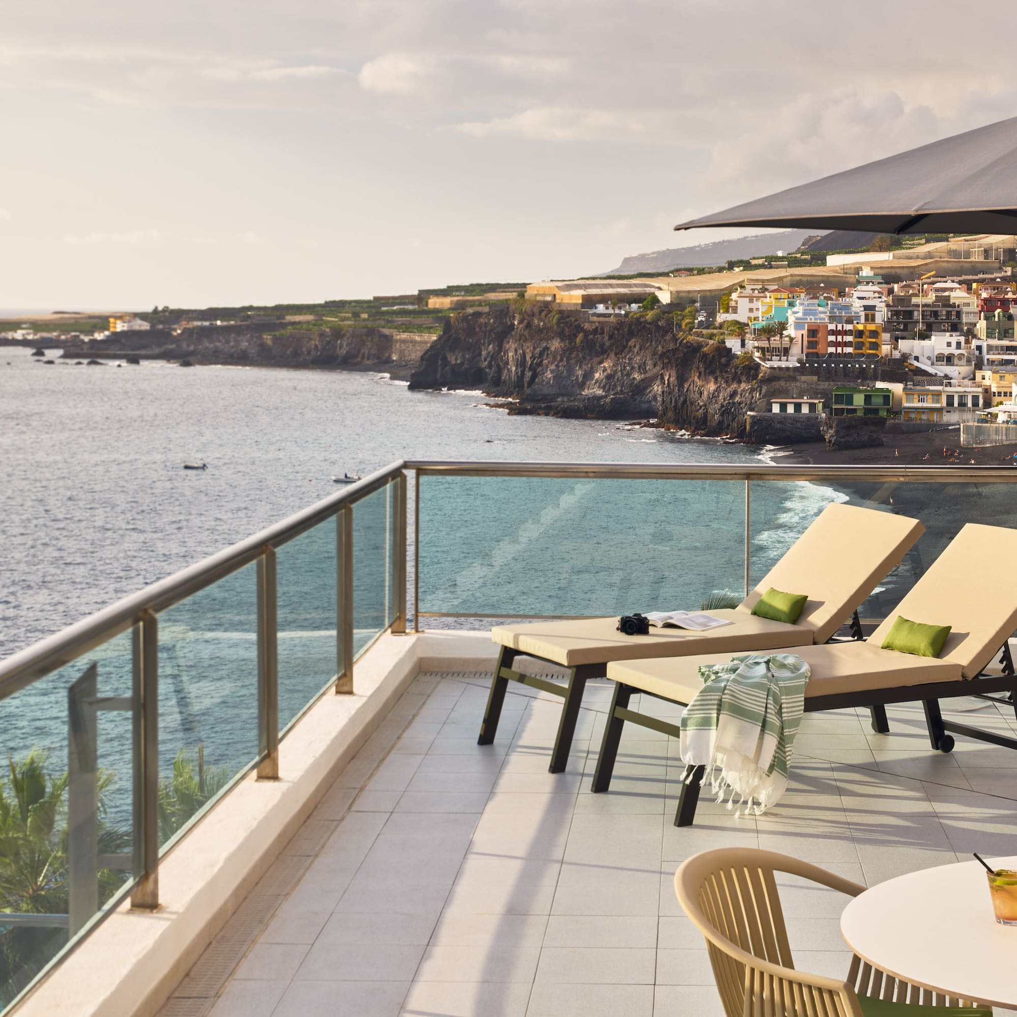 a deck with chairs and a table overlooking the ocean
