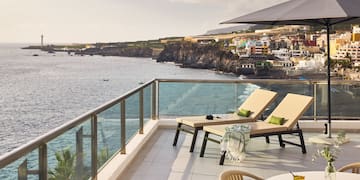 a deck with chairs and a table overlooking the ocean