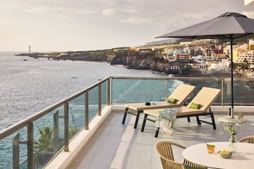 a deck with chairs and a table overlooking the ocean