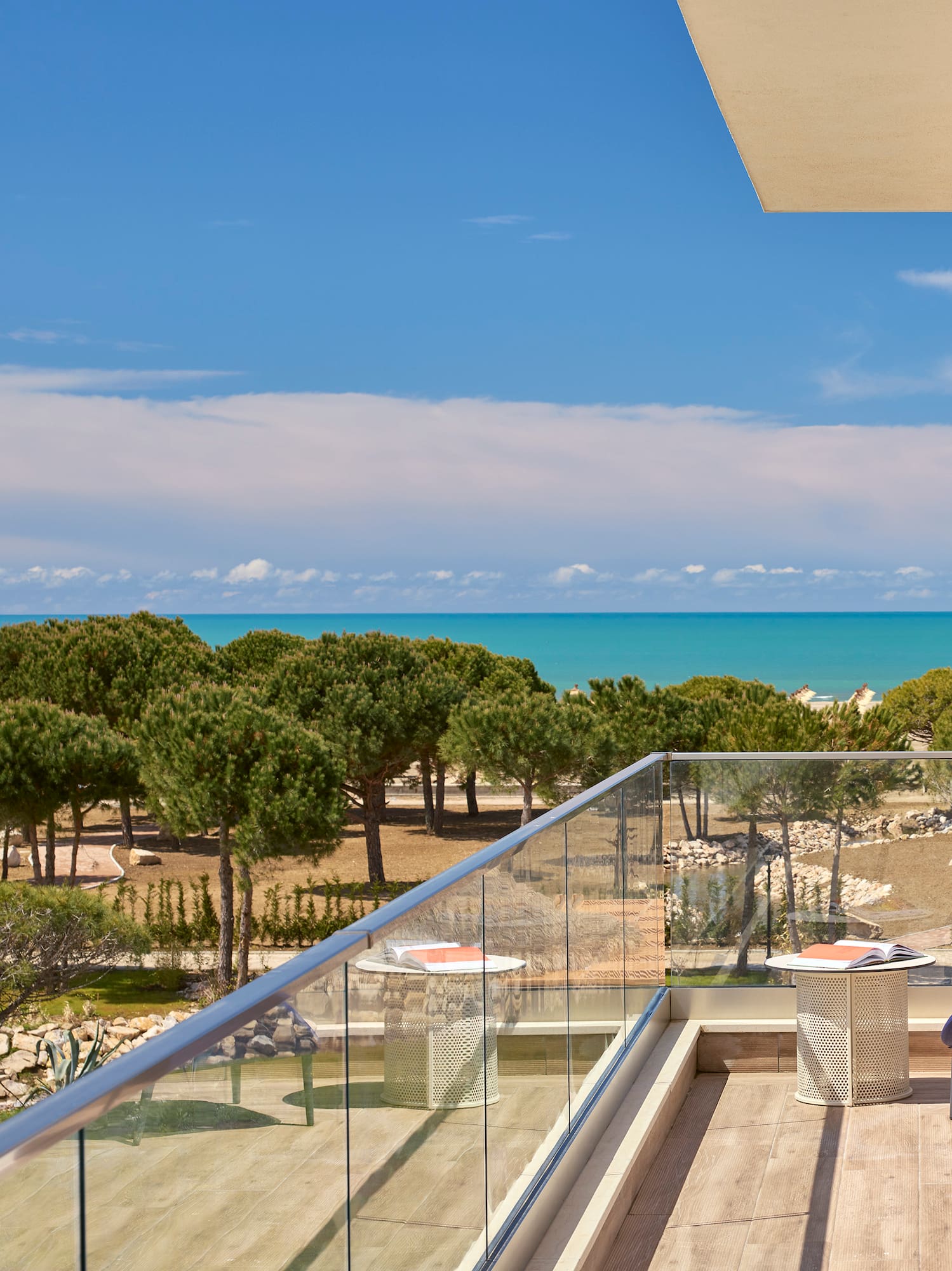 a deck with a chair and a glass railing overlooking a beach