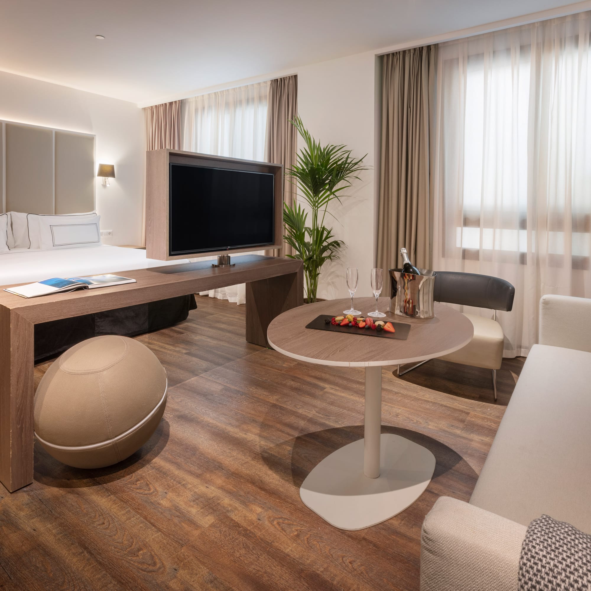 Luxury hotel suite with king bed, TV, lounge area, and welcome champagne.