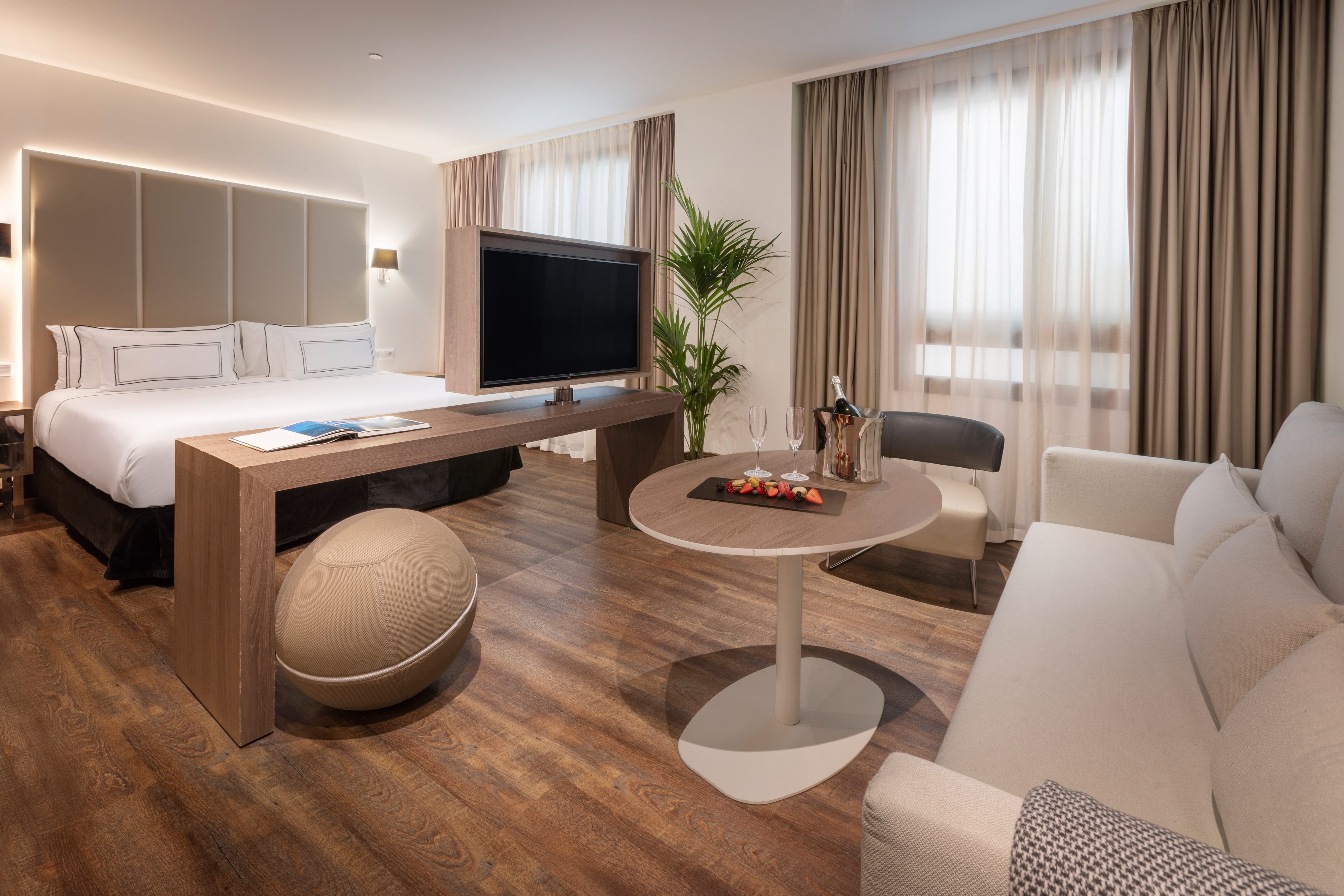 Luxury hotel suite with king bed, TV, lounge area, and welcome champagne.