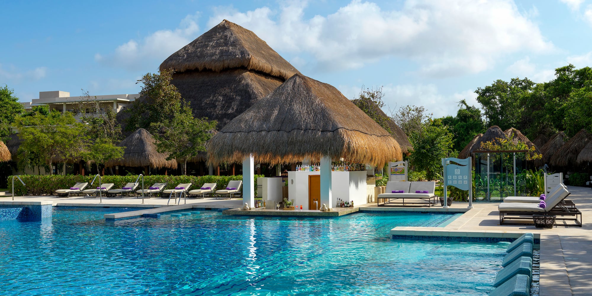 a pool with a building and a thatched roof