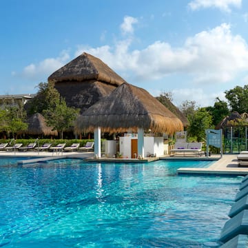 a pool with a building and a thatched roof