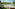 Tropical resort outdoor lounge with infinity pool, lake, and palm trees.