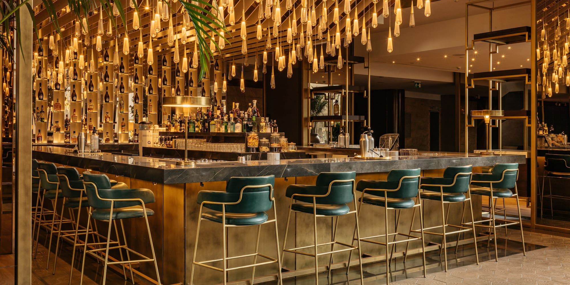a bar with chairs and lights from the ceiling