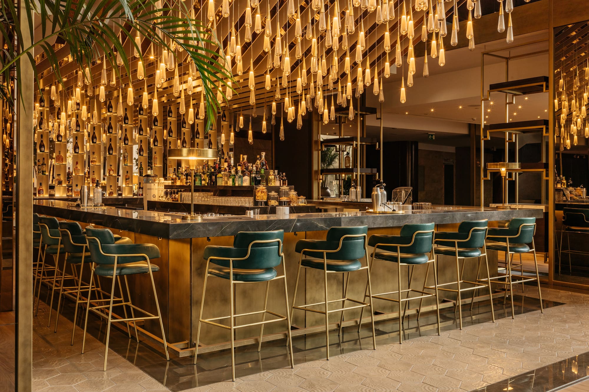 a bar with chairs and lights from the ceiling