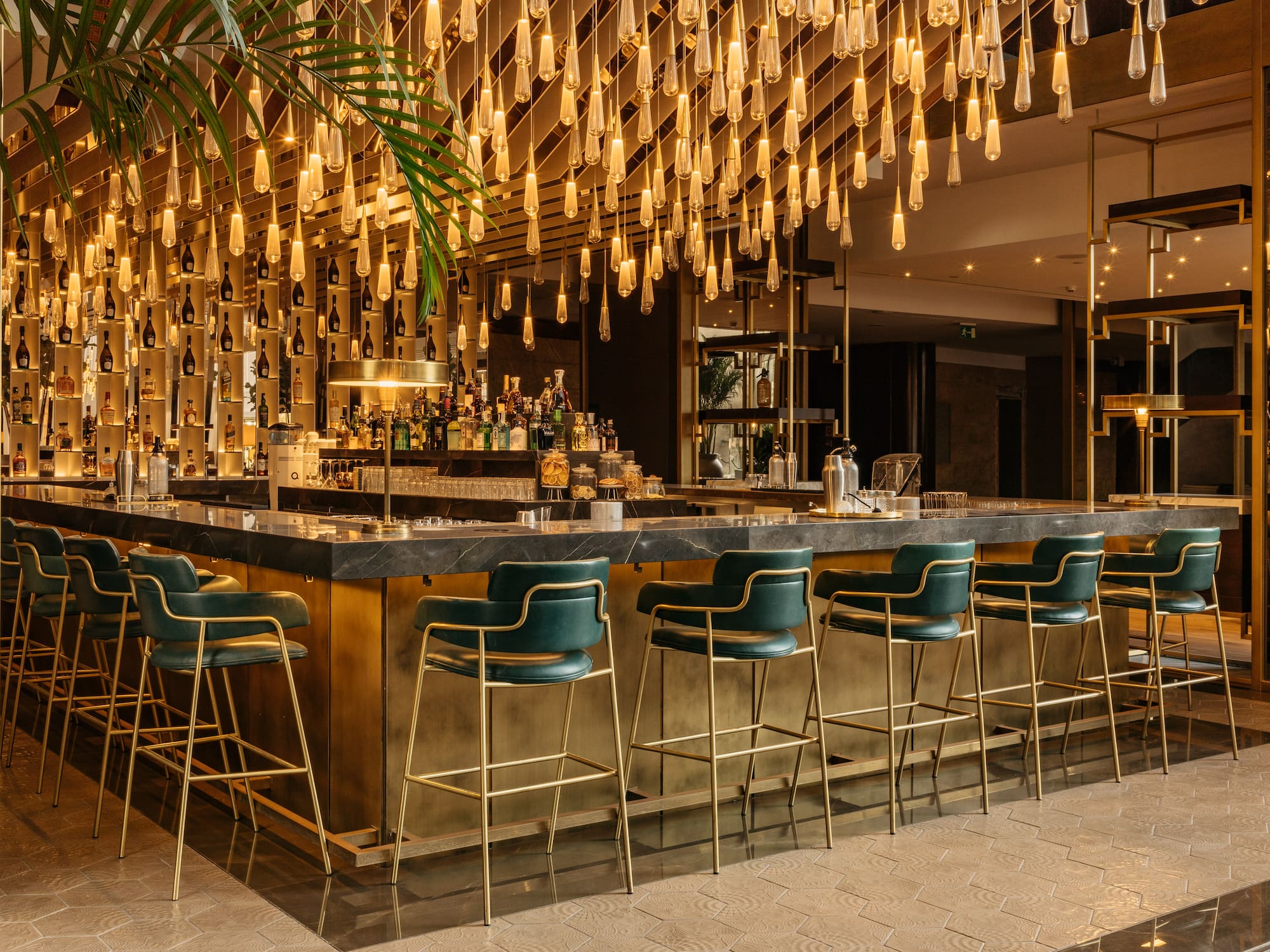 a bar with chairs and lights from the ceiling