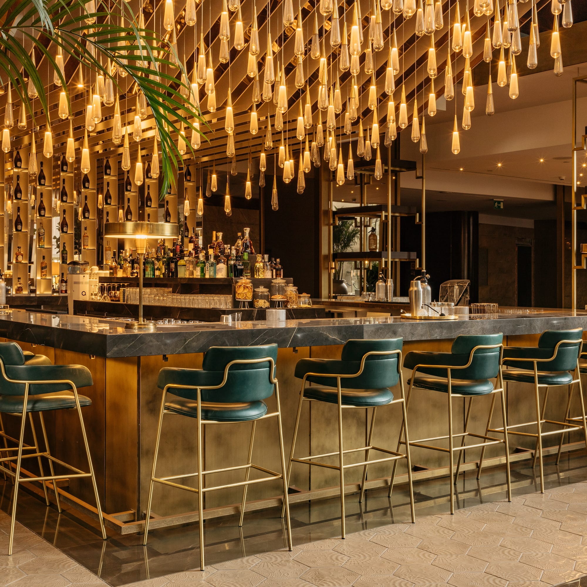 a bar with chairs and lights from the ceiling
