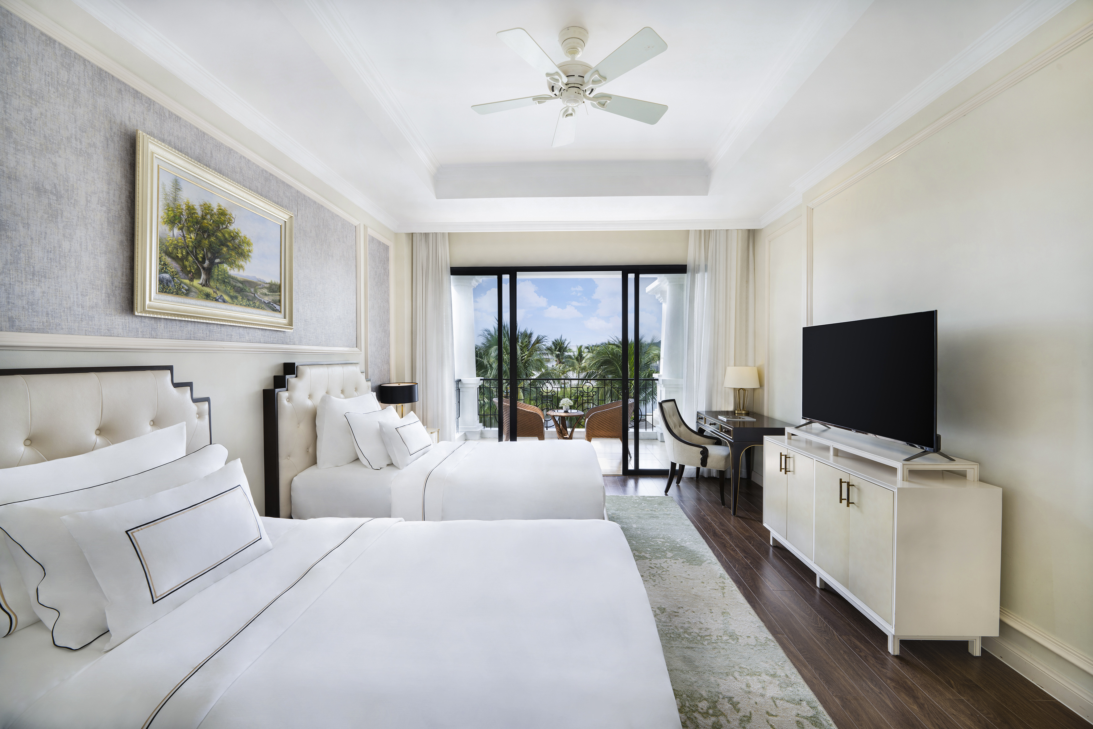Spacious hotel room with two beds, private balcony, and lush tropical view.
