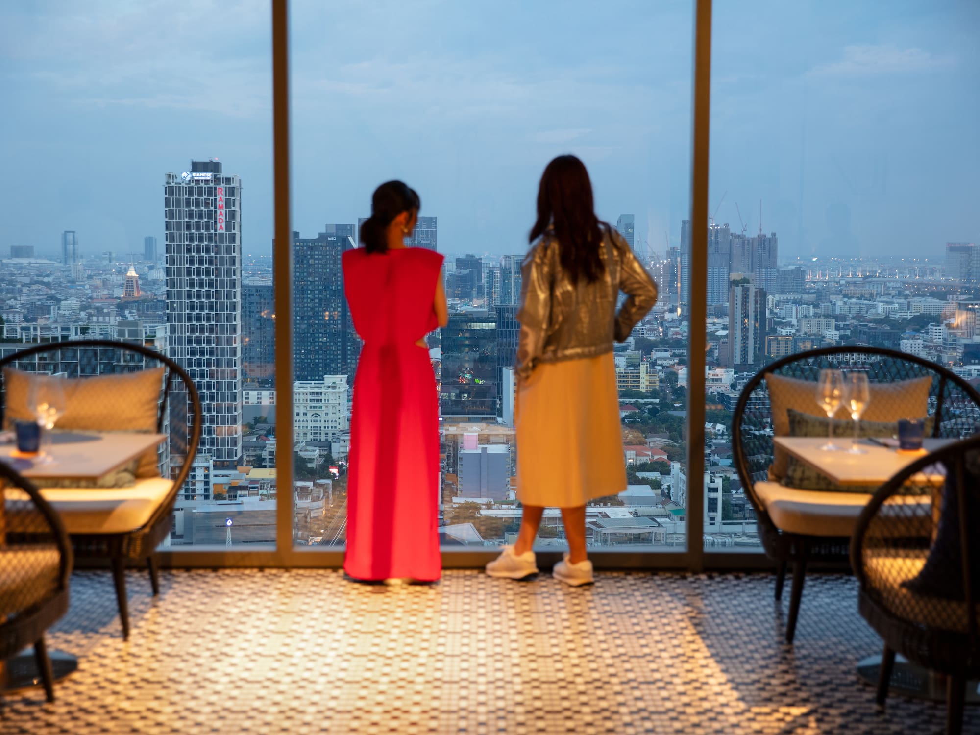 two women looking out a window at a city
