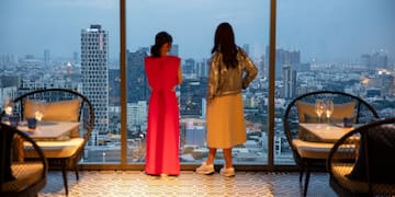 two women looking out a window at a city