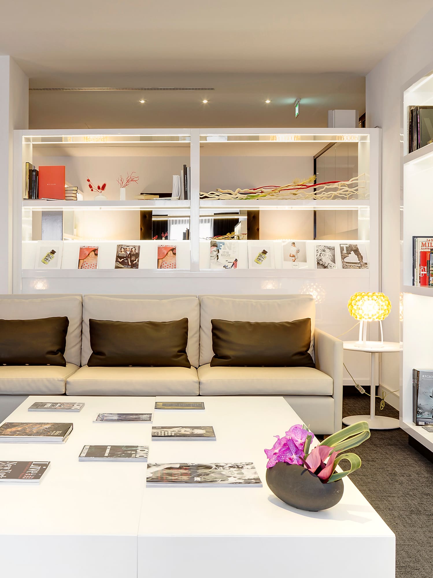 Contemporary lounge with cream sofas, white coffee table, and illuminated shelves.