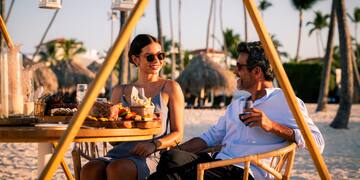 a man and woman sitting at a table with food and drinks