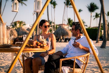 a man and woman sitting at a table with food and drinks
