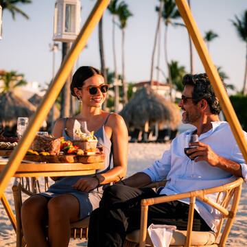 a man and woman sitting at a table with food and drinks