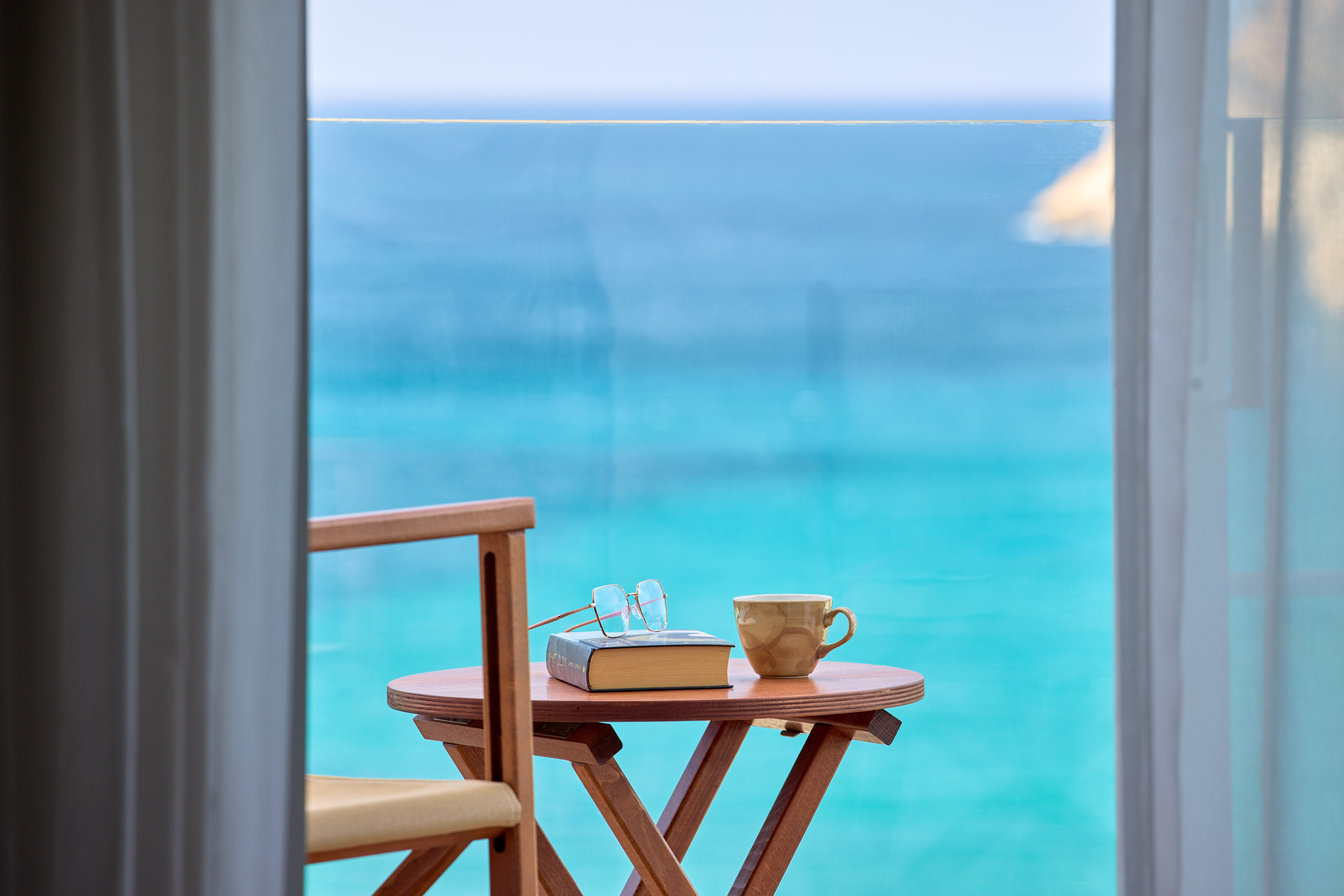 Relaxing ocean view balcony with book, reading glasses, and coffee.