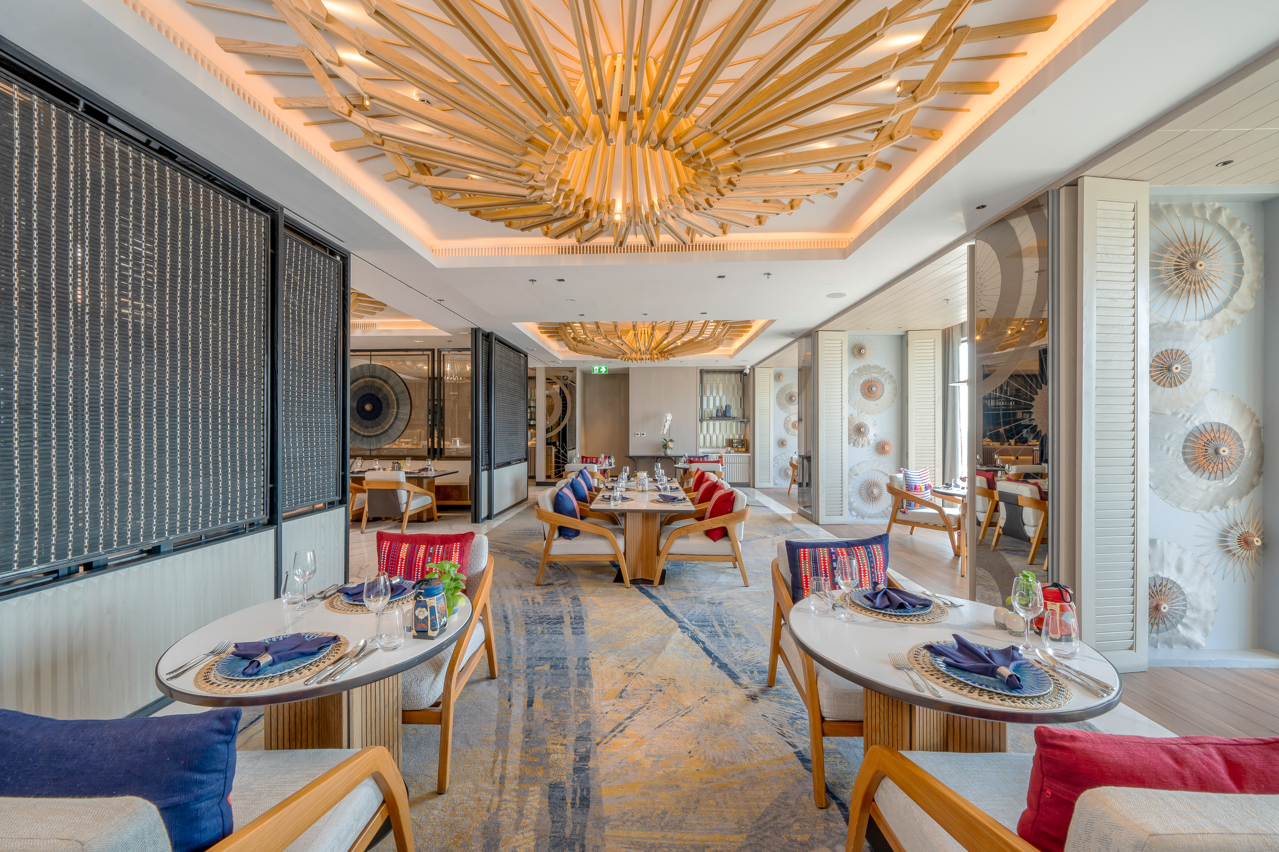 Modern luxury dining room with wooden chandelier, plush seating, and artistic decor.